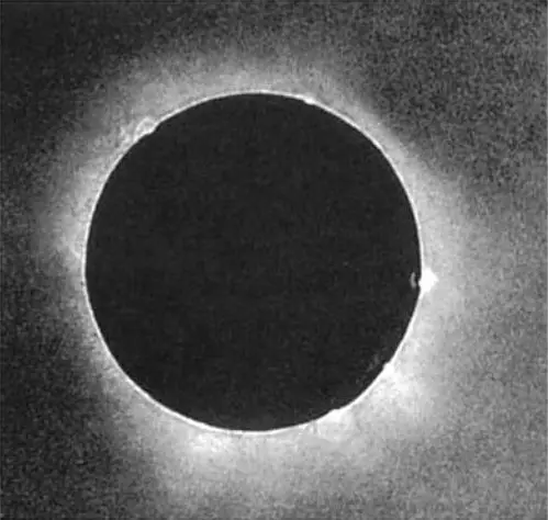 Old photograph: the black disc of the Moon with a pale, uneven glow of the corona around it.