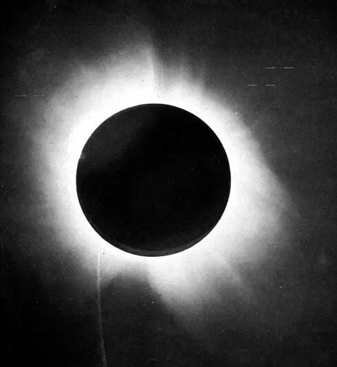 Photographic plate: the dark disc of the Moon with the white corona; small dashes mark the stars that were measured.